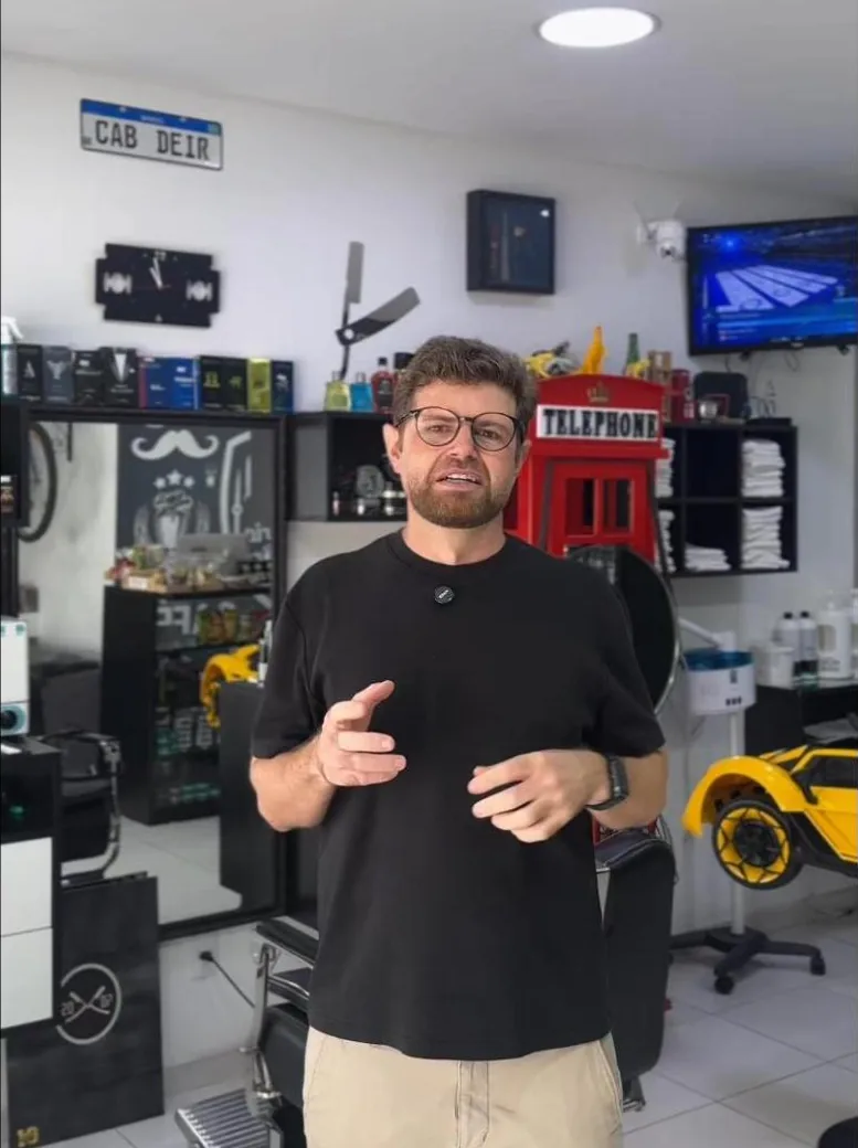 Deir dentro do salão, com cadeiras de barbeiro, cabine telefônica vermelha e carrinho amarelo